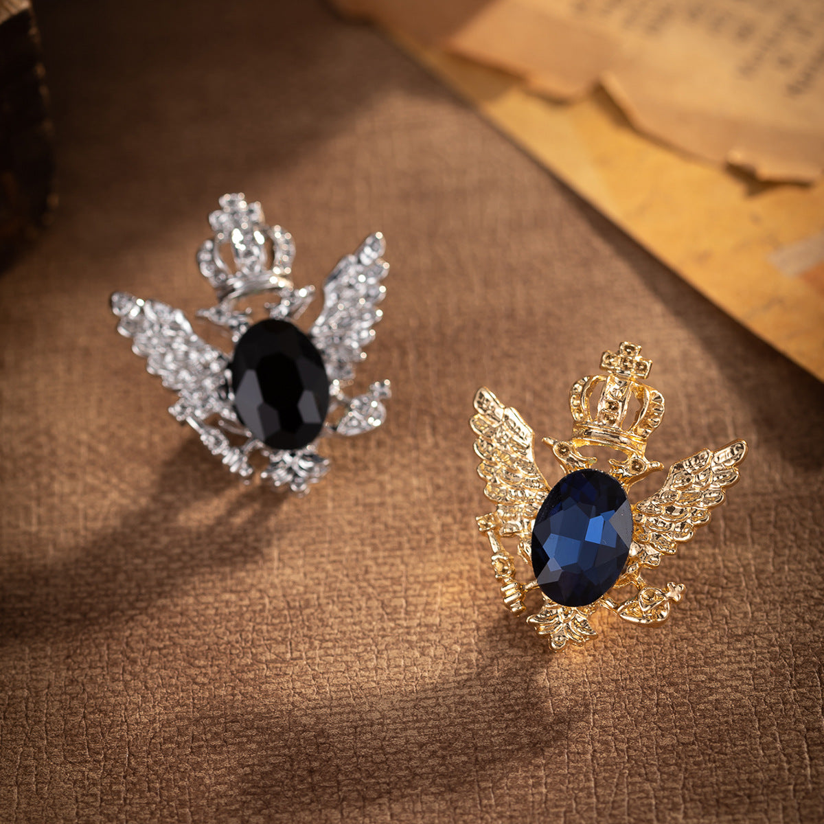 Crystal eagle brooches: silver and gold versions with crown, wings, and dark oval stones