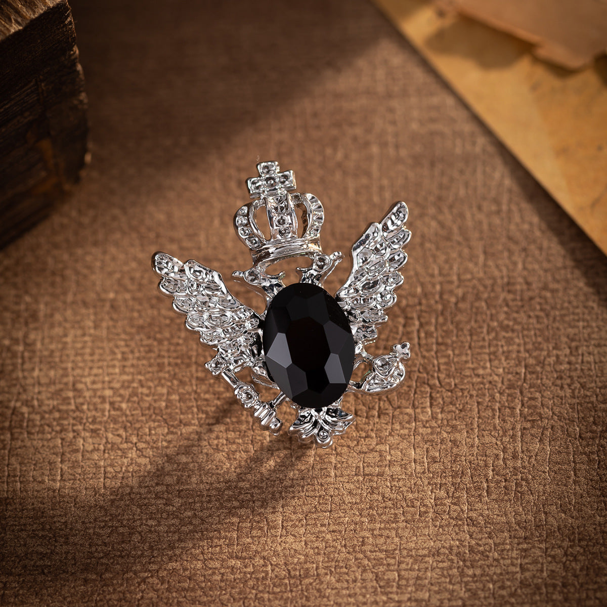 Silver winged eagle brooch with crown, detailed wings, and dark oval crystal centerpiece