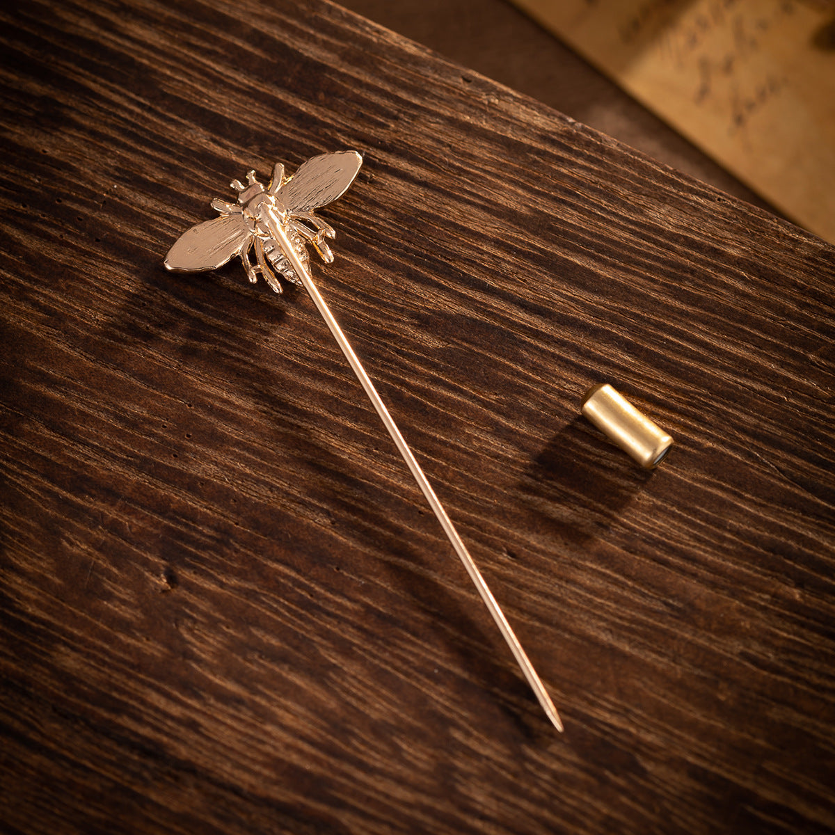 Gold-tone bee brooch pin with raised body and wing detailing, straight stick back