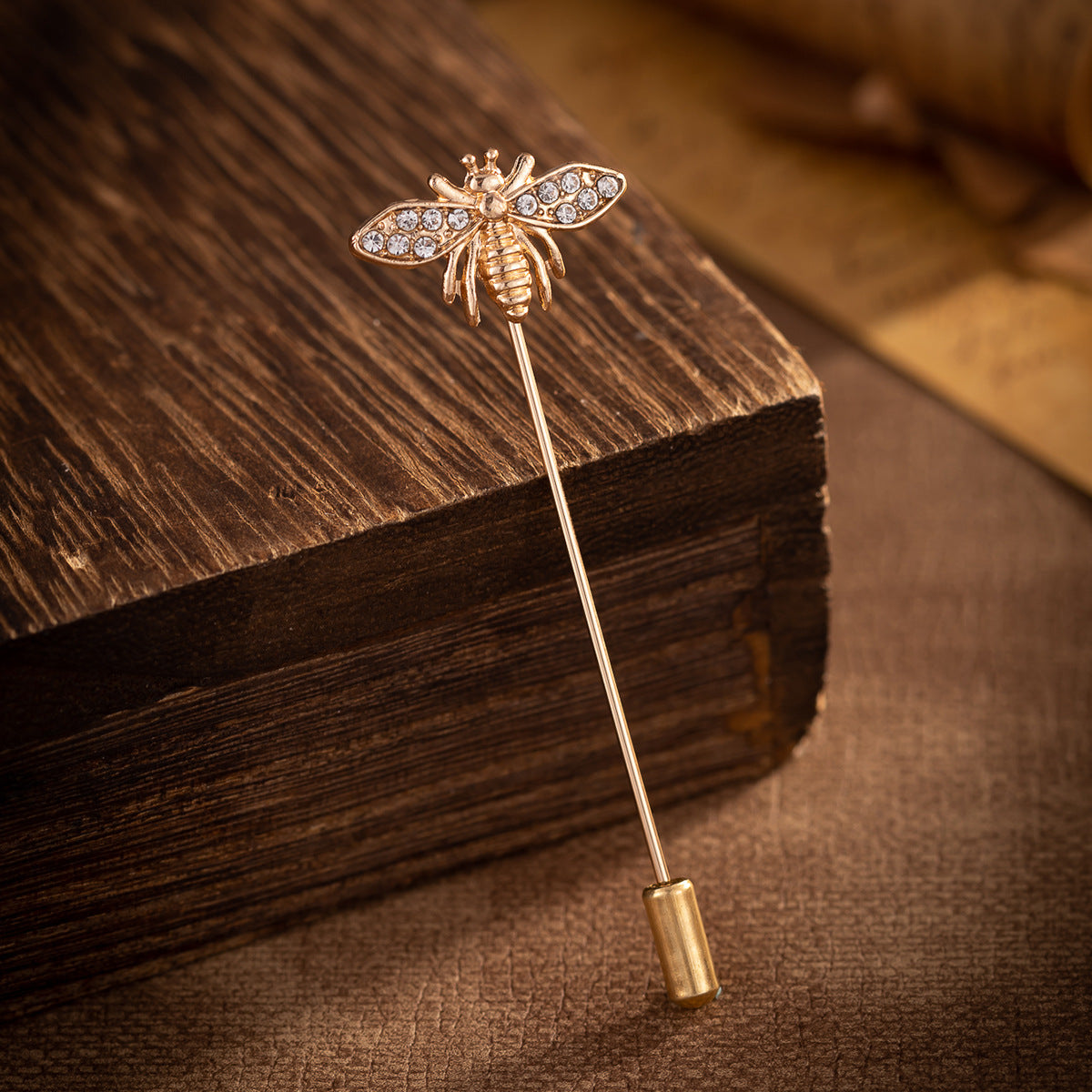 Gold-tone bee brooch pin with rhinestone wings and hinged clasp on the pin