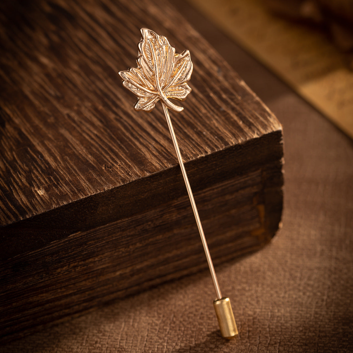 Gold-tone maple leaf brooch pin with textured leaf veins and straight post