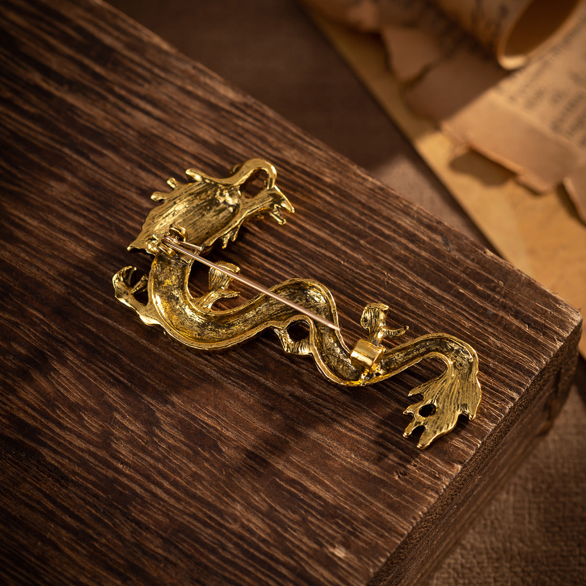 Antique gold dragon totem brooch with clasp pin on dark wooden surface
