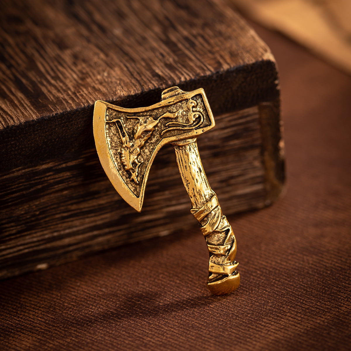 Gold axe brooch close-up, angled view on wood