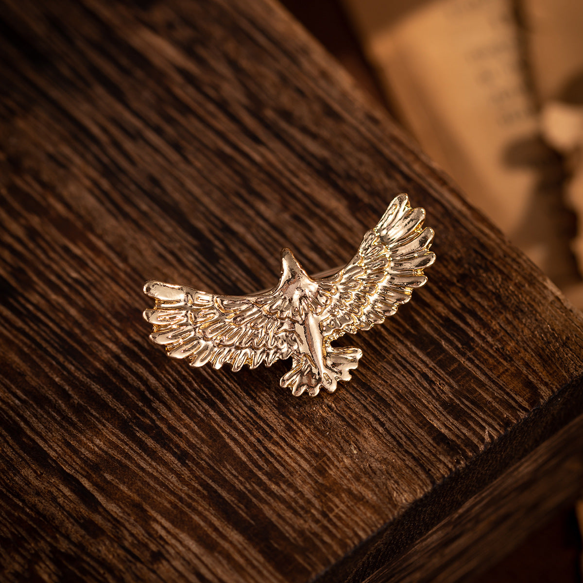 Gold-tone bird brooch with outstretched wings and small central eagle figure