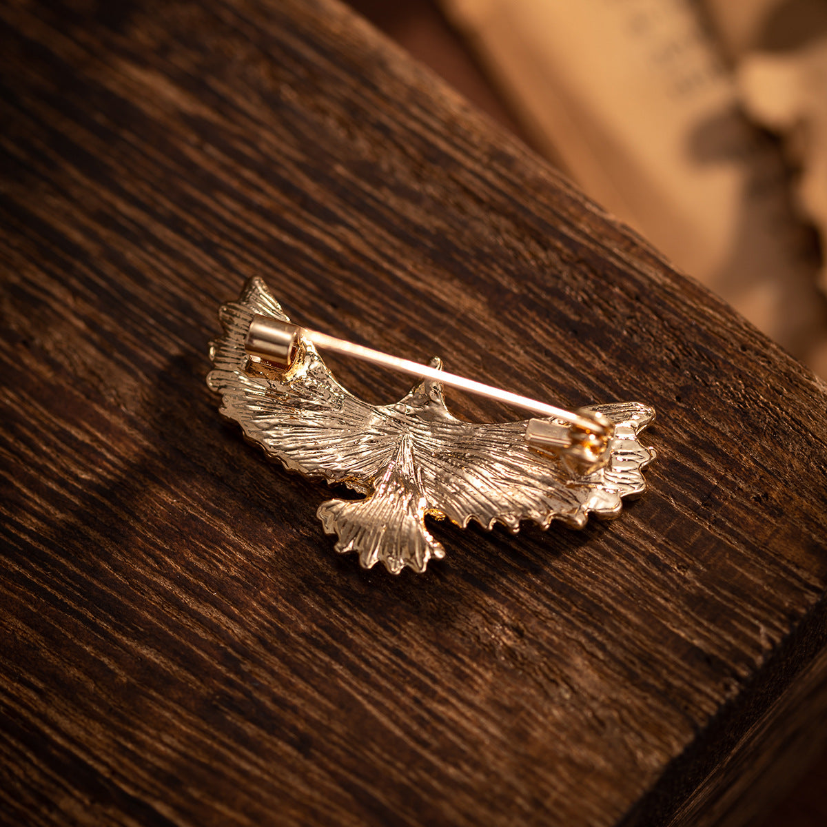Gold-tone eagle brooch with open wings and metal pin back, close-up view