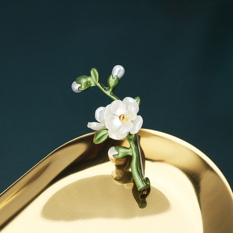 Green 3D leaf brooch pin with white flower petals, green leaves, and small gold center