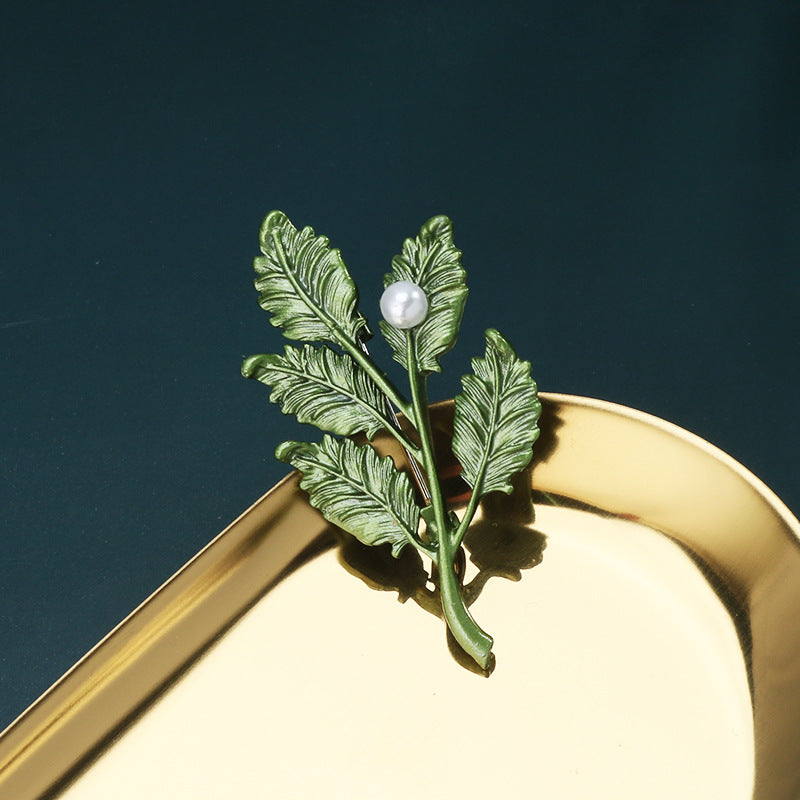 Green 3D leaf brooch pin with textured leaves and a single white pearl center
