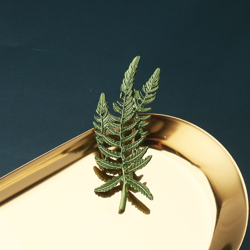 Green 3D leaf brooch pin with layered fern-like leaves on a single stem