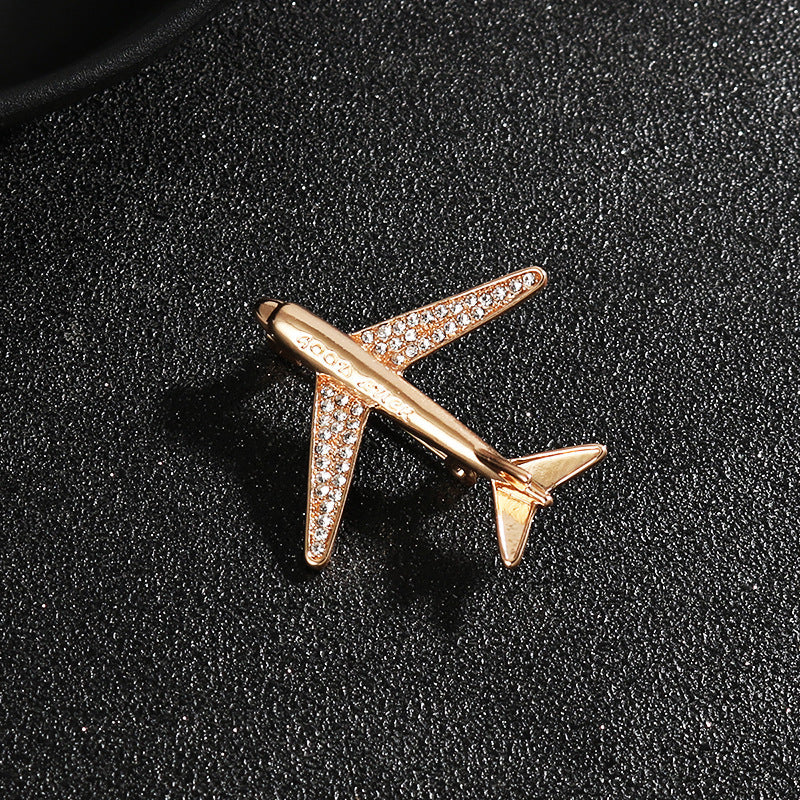 Gold airplane brooch pin with rhinestone sparkle detail on wings and fuselage