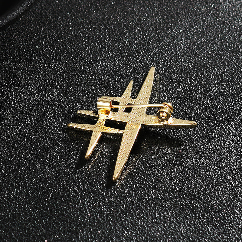 Gold cross-shaped starburst brooch pin with rhinestone accents and clasp