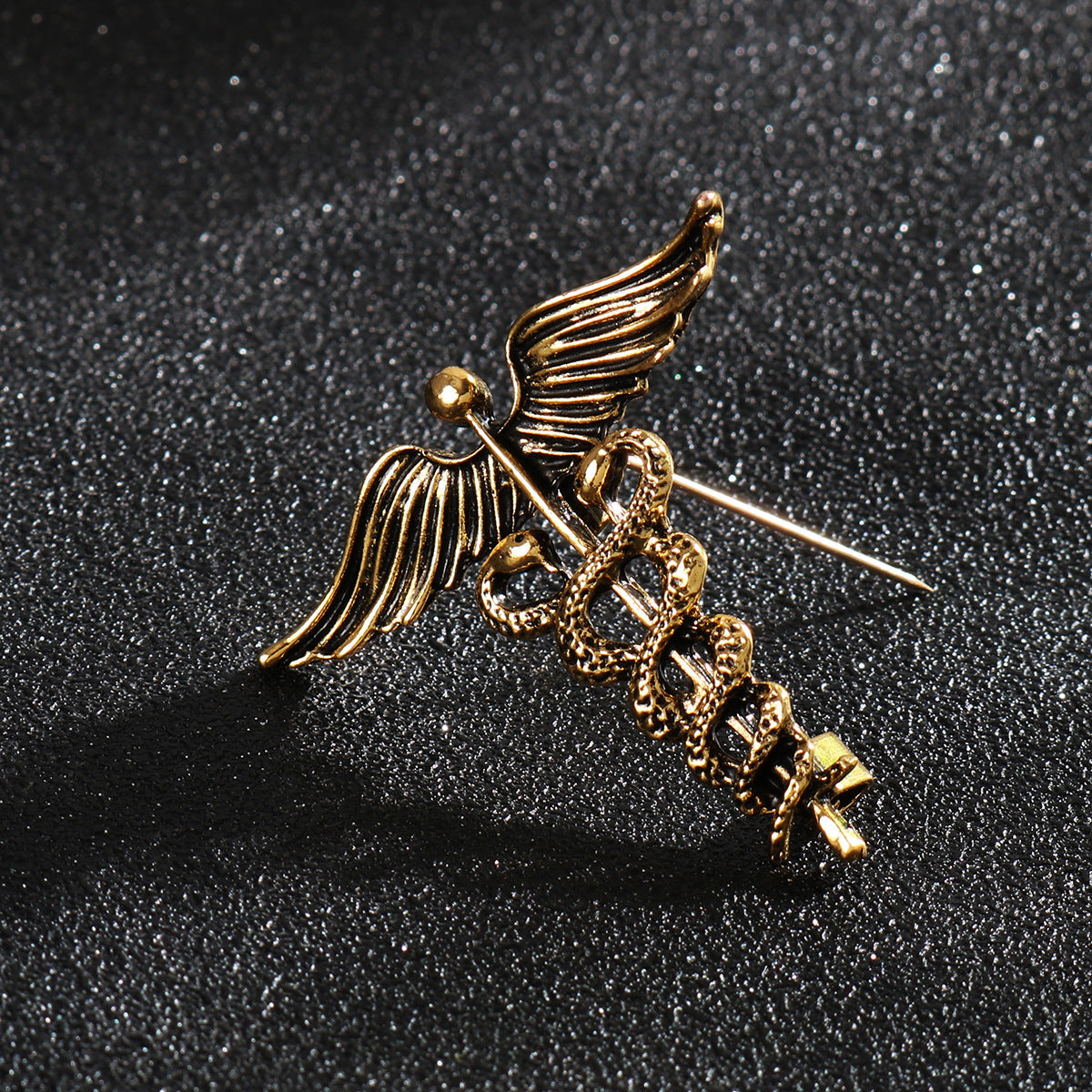 Gold snake and angel wings brooch pin, close-up metal detail