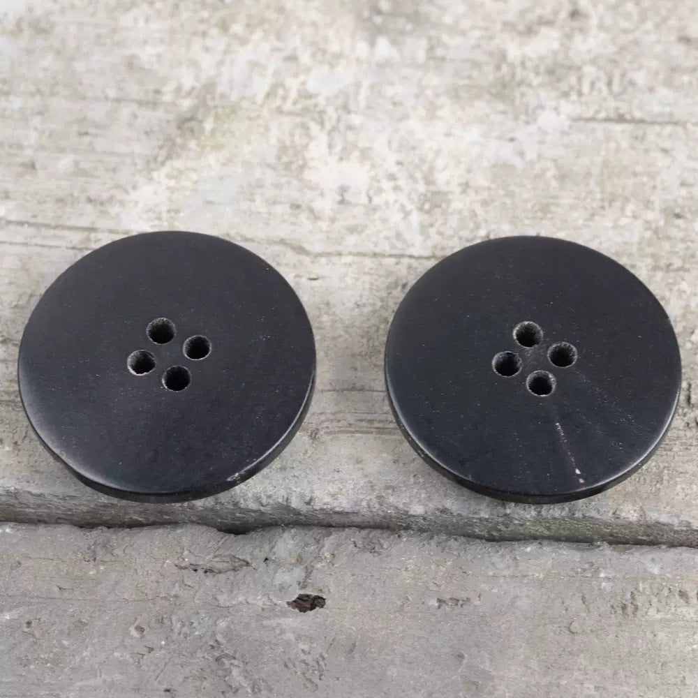 Black convex horn button backs with 4-hole shank holes, smooth round disc