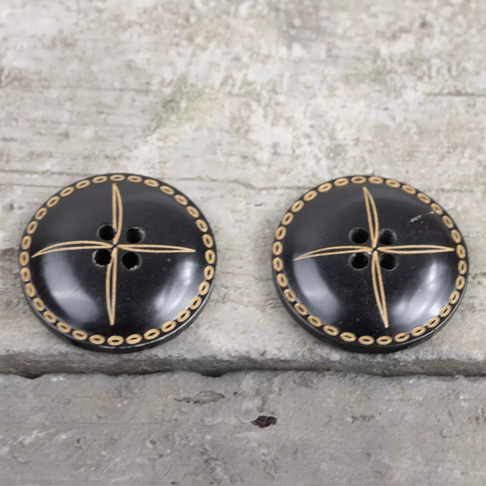Pair of black convex horn buttons with gold ring border and engraved cross starburst