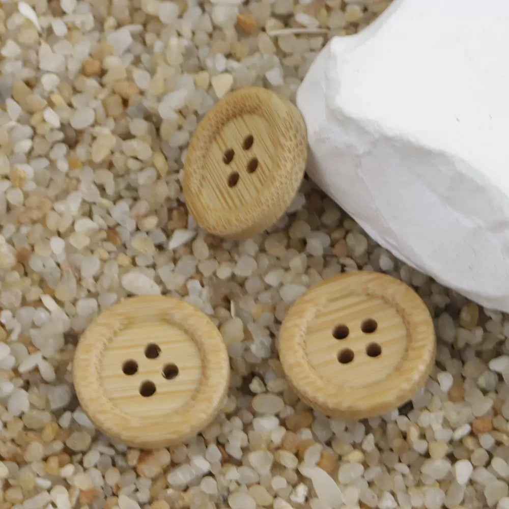 Natural bamboo buttons with four-hole pattern, round tops and wood grain visible