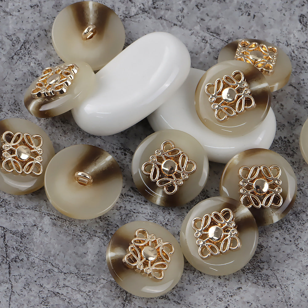 Round metal-and-resin buttons with shanks, decorative clover filigree on cream and tan faces