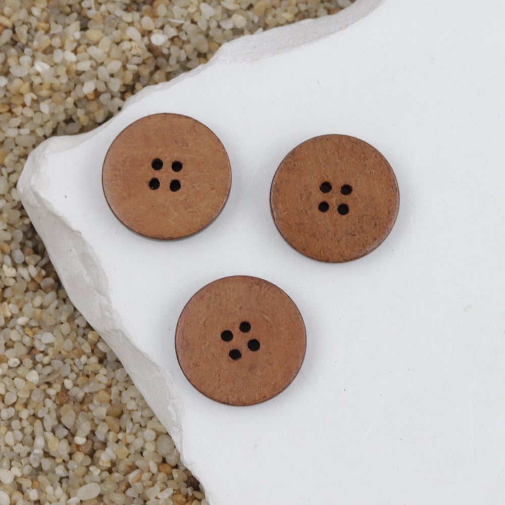 Round tan/brown wooden buttons with four holes, set on white fabric