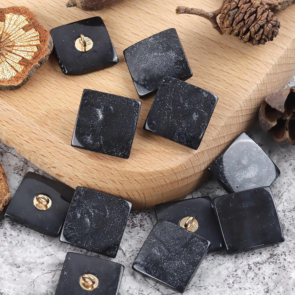 Black square pearlized ripple shank buttons with gold loops, speckled finish
