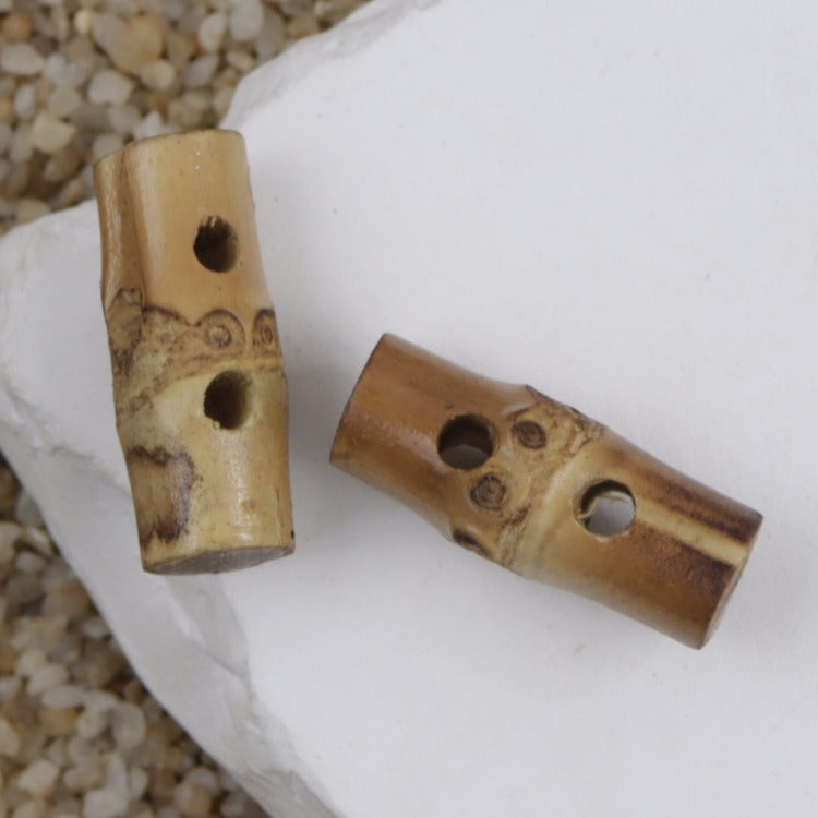 Two natural bamboo two-hole toggle buttons with circular holes and knot motif