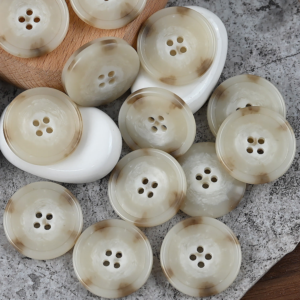 Round 4-hole urea buttons in cream and off-white tones, arranged on white pads