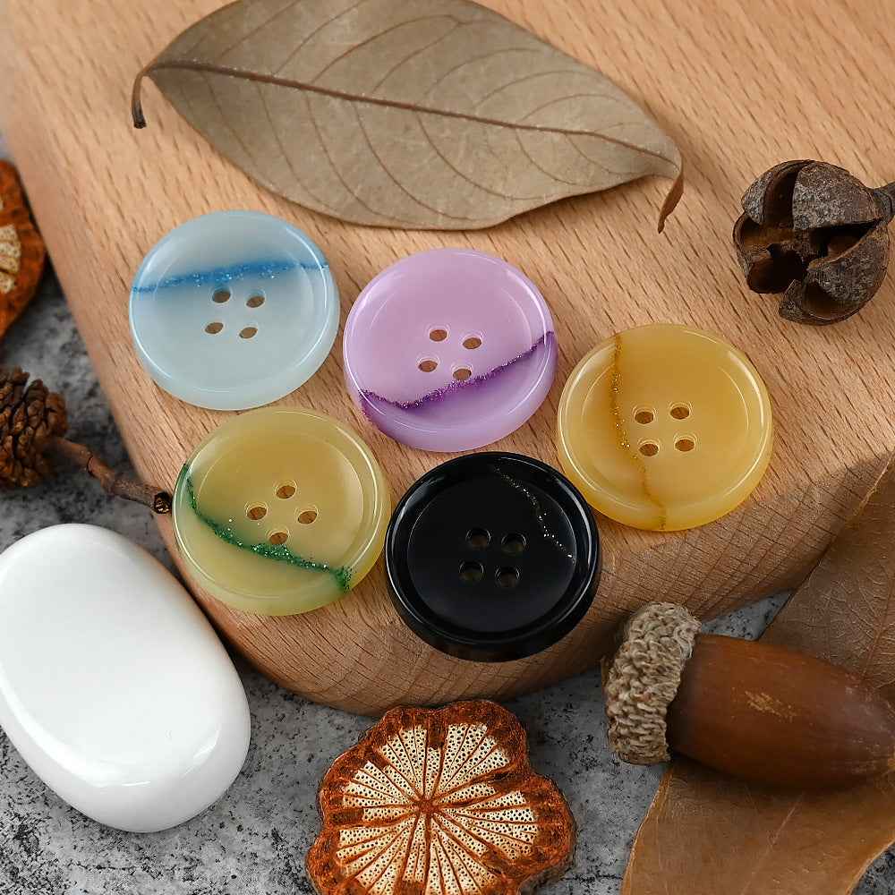 Assorted round 4-hole urea buttons in light blue, purple, pale yellow-green, and black