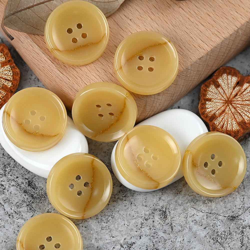 Round 4-hole urea buttons in yellow tones, with subtle warm streaks