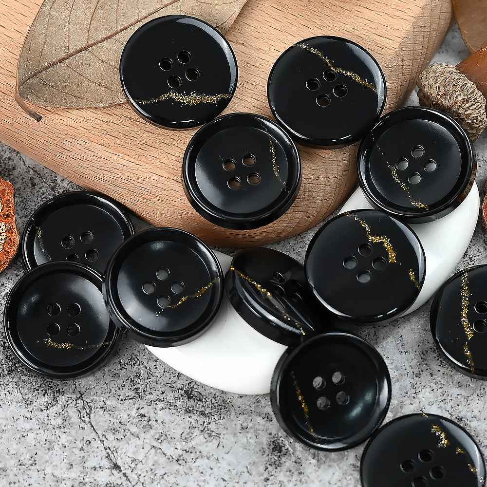 Round 4-hole urea buttons in black with faint gold speckle along the edge