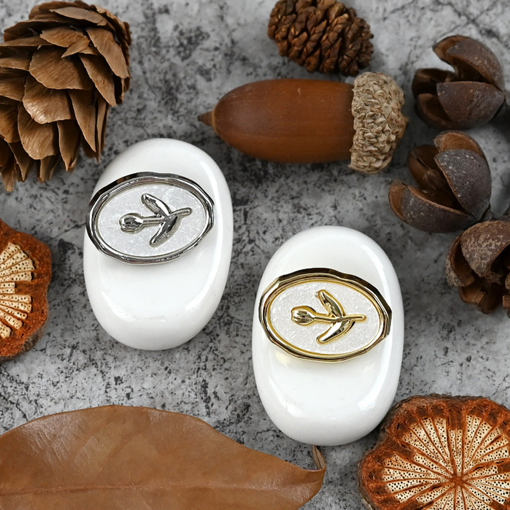 Tulip oval metal shank buttons in gold and silver, on white oval backs
