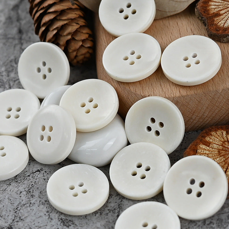 Set of white round 4-hole buttons, each with four center holes for fastening