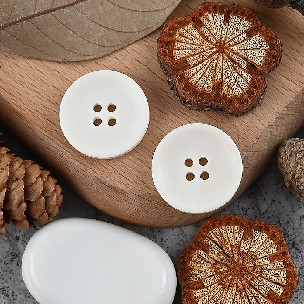 White round buttons with four holes, arranged on a surface for classic tailoring