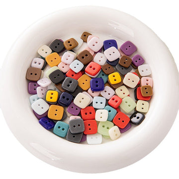 Square 2-hole ceramic kids buttons in mixed colors, in white bowl