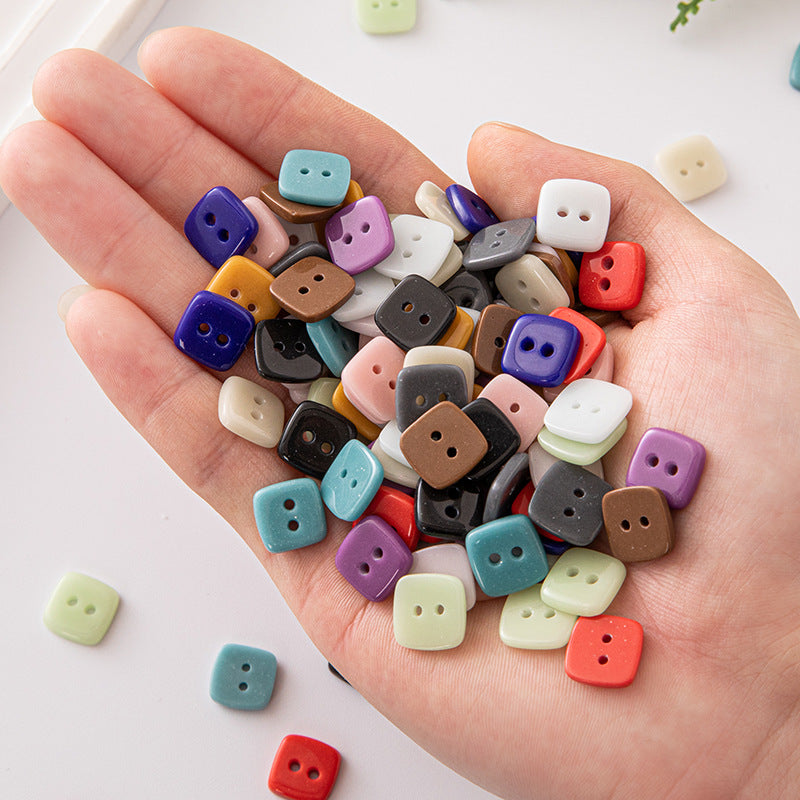 Square 2-hole ceramic buttons in mixed colors held in open hand