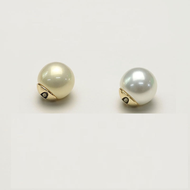 Two white glossy pearl coat buttons with gold-tone metal base and loop hole
