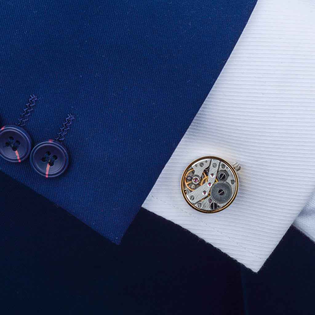 Gold mechanical watch movement cufflinks on a dress shirt cuff, round gear face