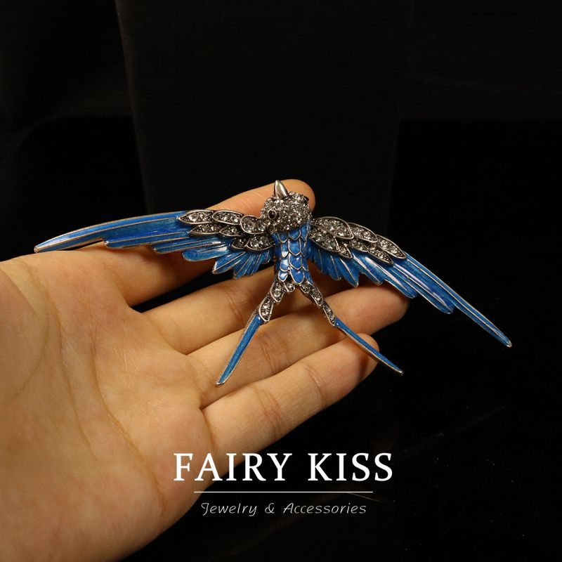 Blue enamel swallow brooch in hand, crystal wings and three-prong pin backing