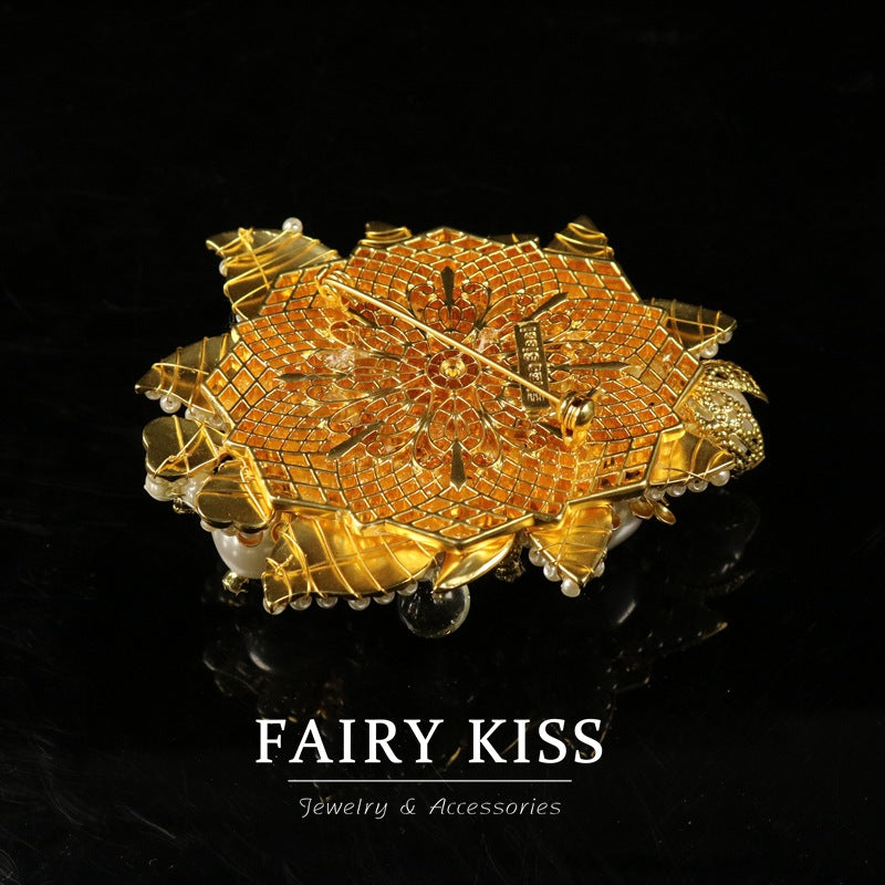 Gold mesh-style flower brooch with textured center and dangling beaded accents.