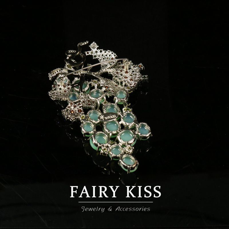 Green glass grape brooch with ornate metal setting and dangling round beads