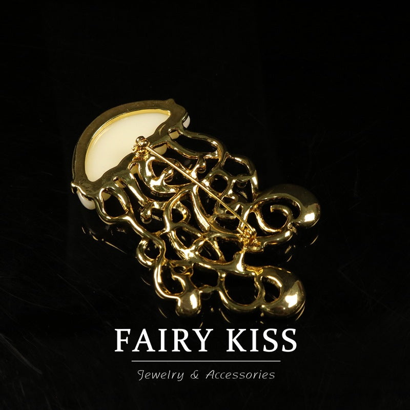 Gold-tone jellyfish brooch with rhinestone detail and decorative looping metalwork