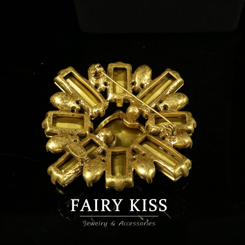 Gold-toned geometric rhinestone brooch with textured prong settings and crystal details