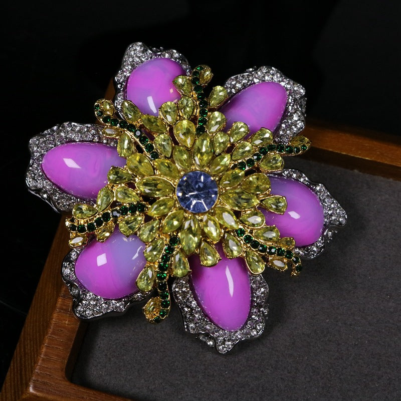 Pink gemstone-style flower brooch with silver rhinestone border, gold leaves, blue center