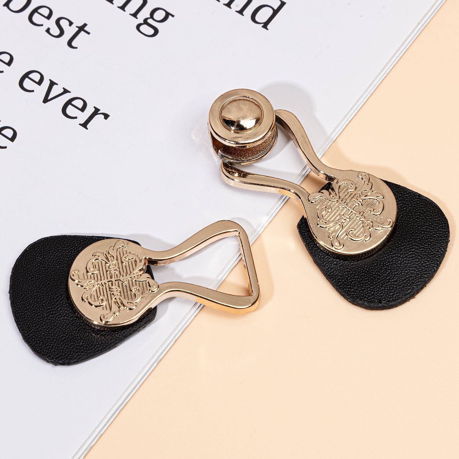 Close view of black leather toggle with gold-tone metal ring and engraved plate