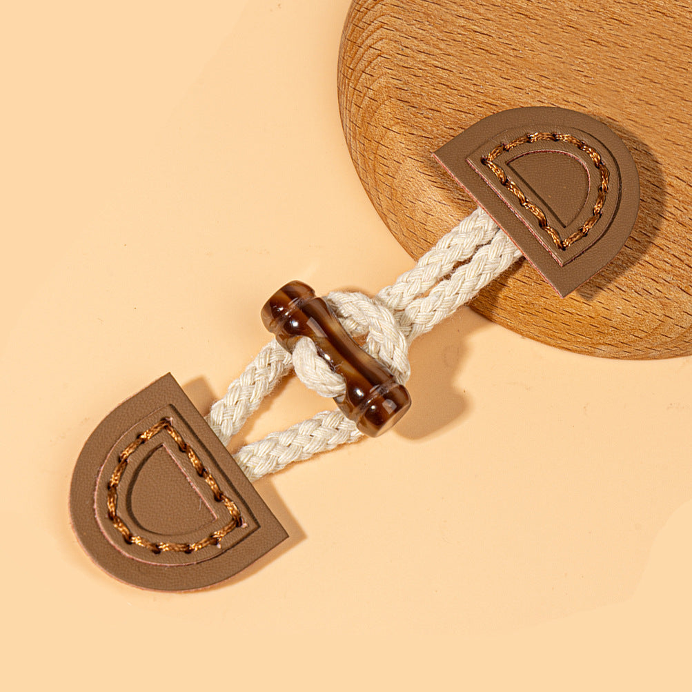 Brown leather sew-on toggle with white braided cord and dark ring fastener