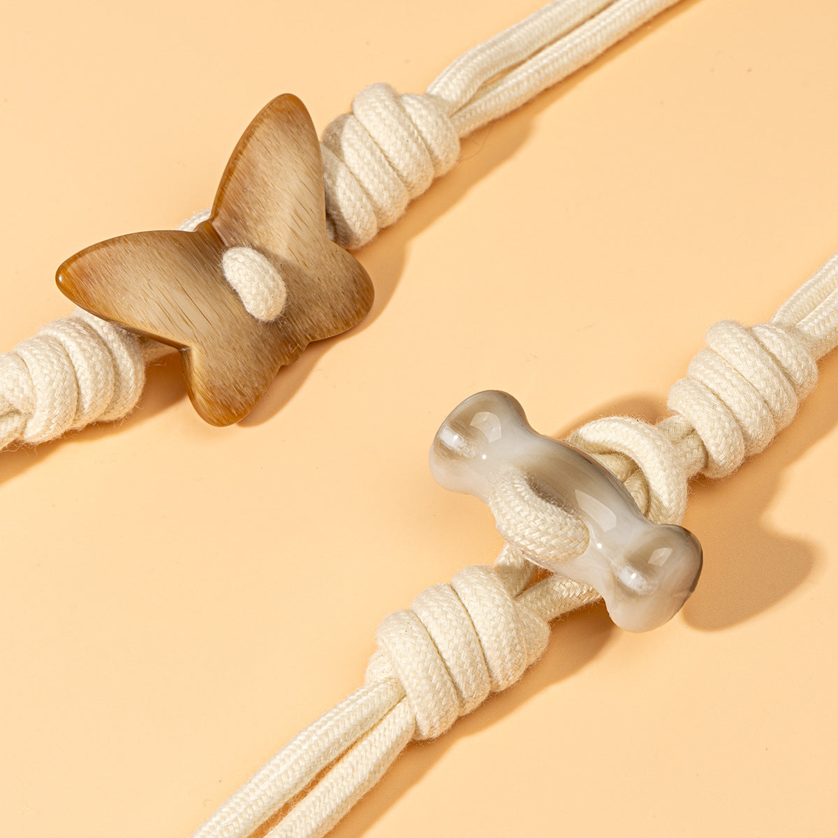 Close-up butterfly toggle: wooden butterfly detail on white braided cord with clear resin tips
