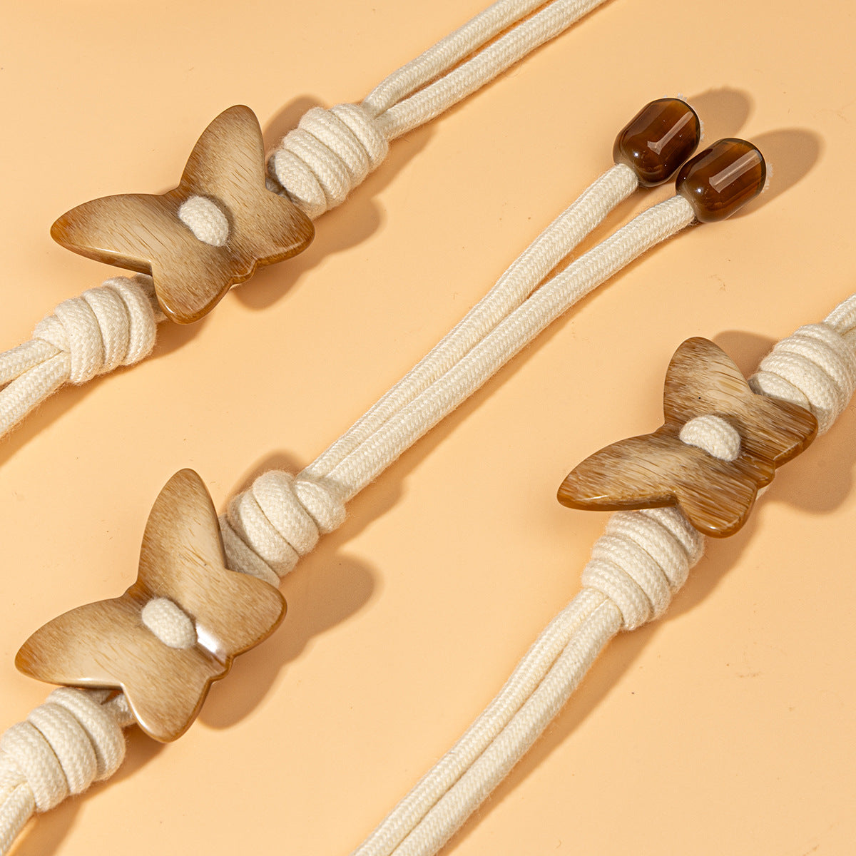 Four butterfly toggle buttons, white rope cords with wooden butterflies and amber resin caps