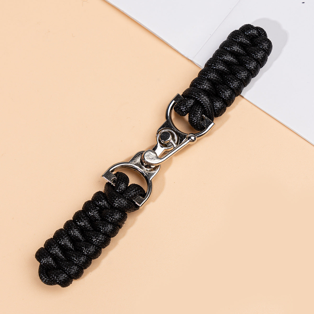Black waxed-rope sew-on toggle button with metal buckle, close-up