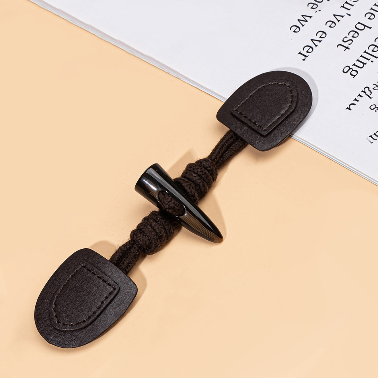 Black leather sew-on button with resin horn spike and braided cord loop, close-up