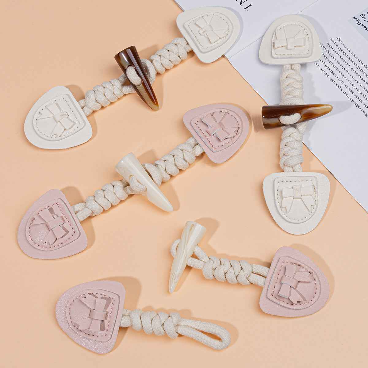 Set of 4 children's coat buckles: pink, beige, and white with braided cords and horn tips