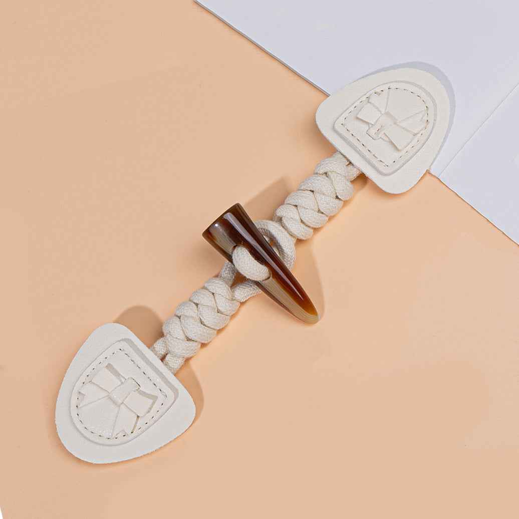 Beige/white coat buckle with braided cord and horn tip, heart-shaped backing