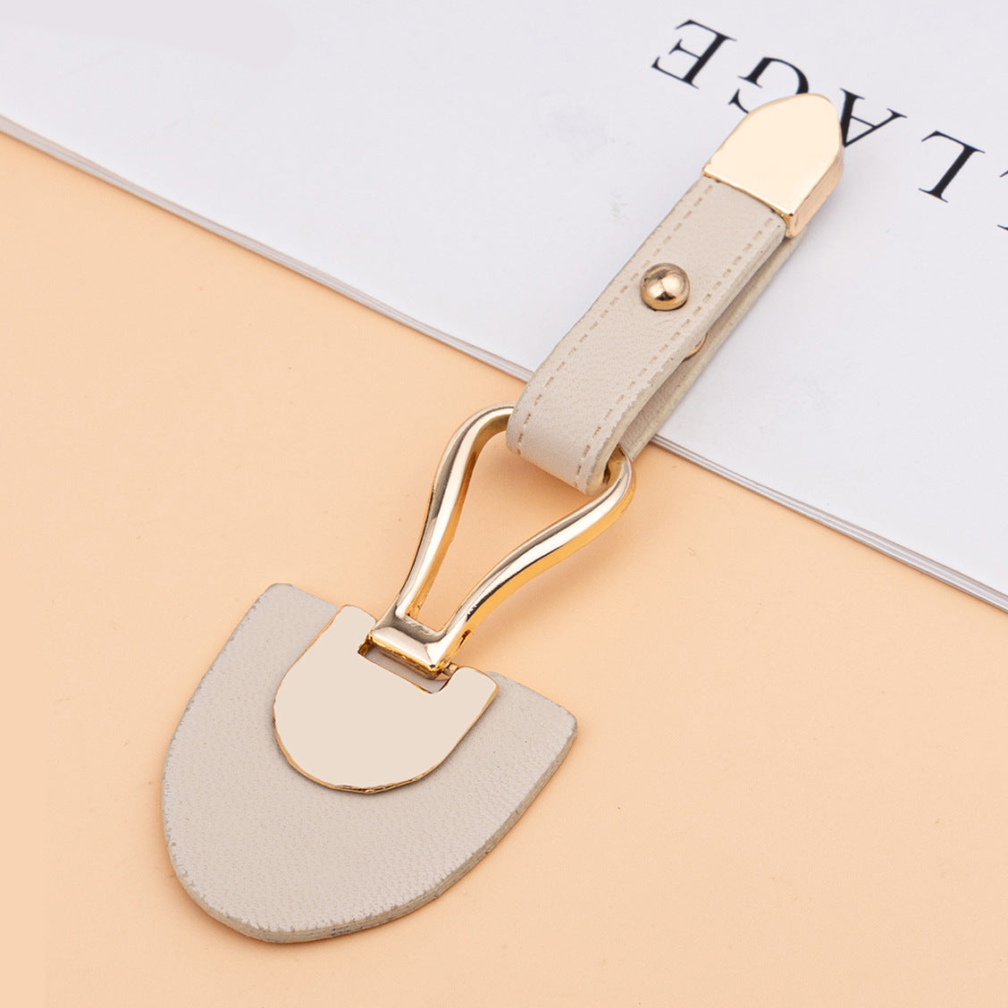 Beige leather sew-on toggle with gold metal buckle and rivet