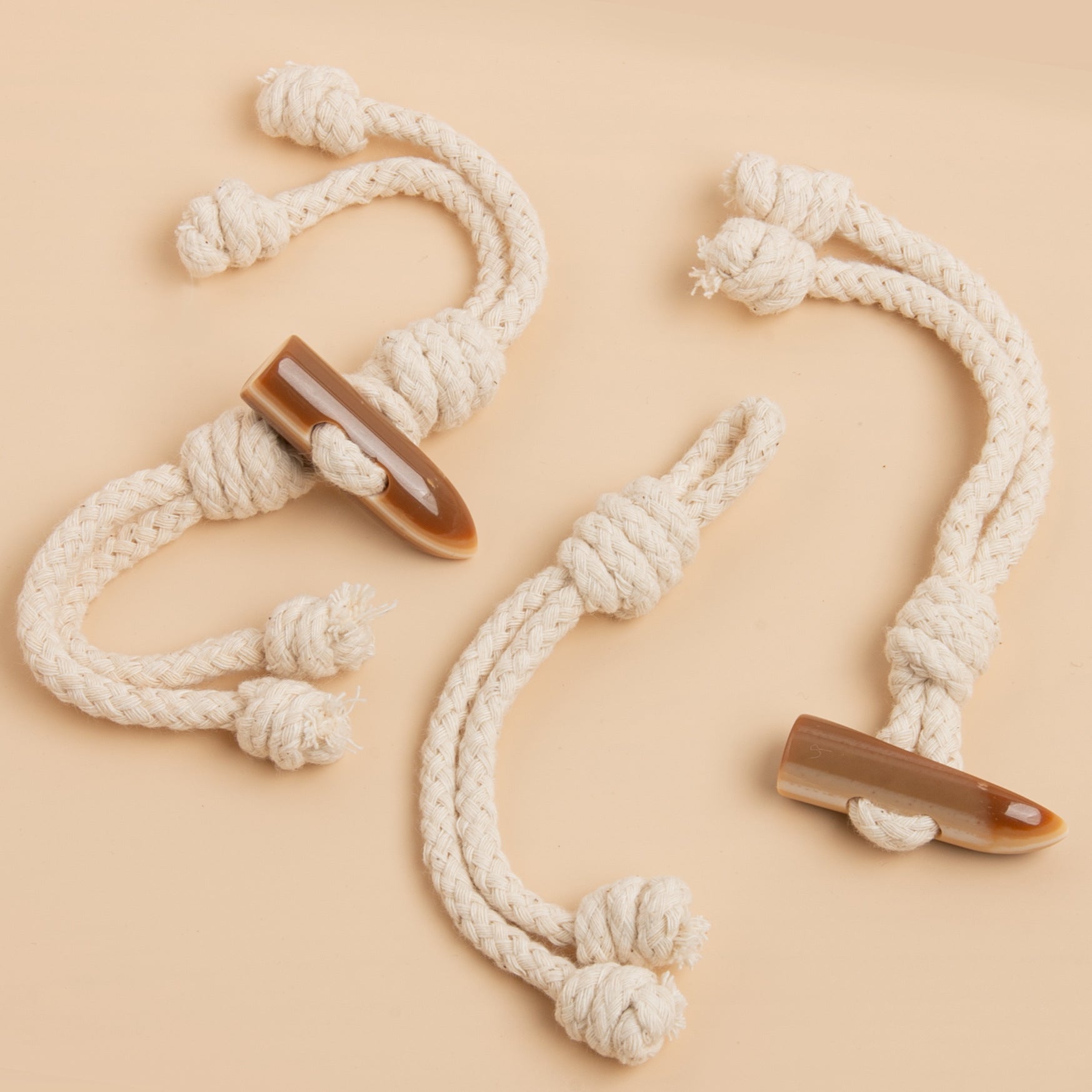 Beige rope tassel buckles with horn-shaped resin tips, 3pcs arranged for close view