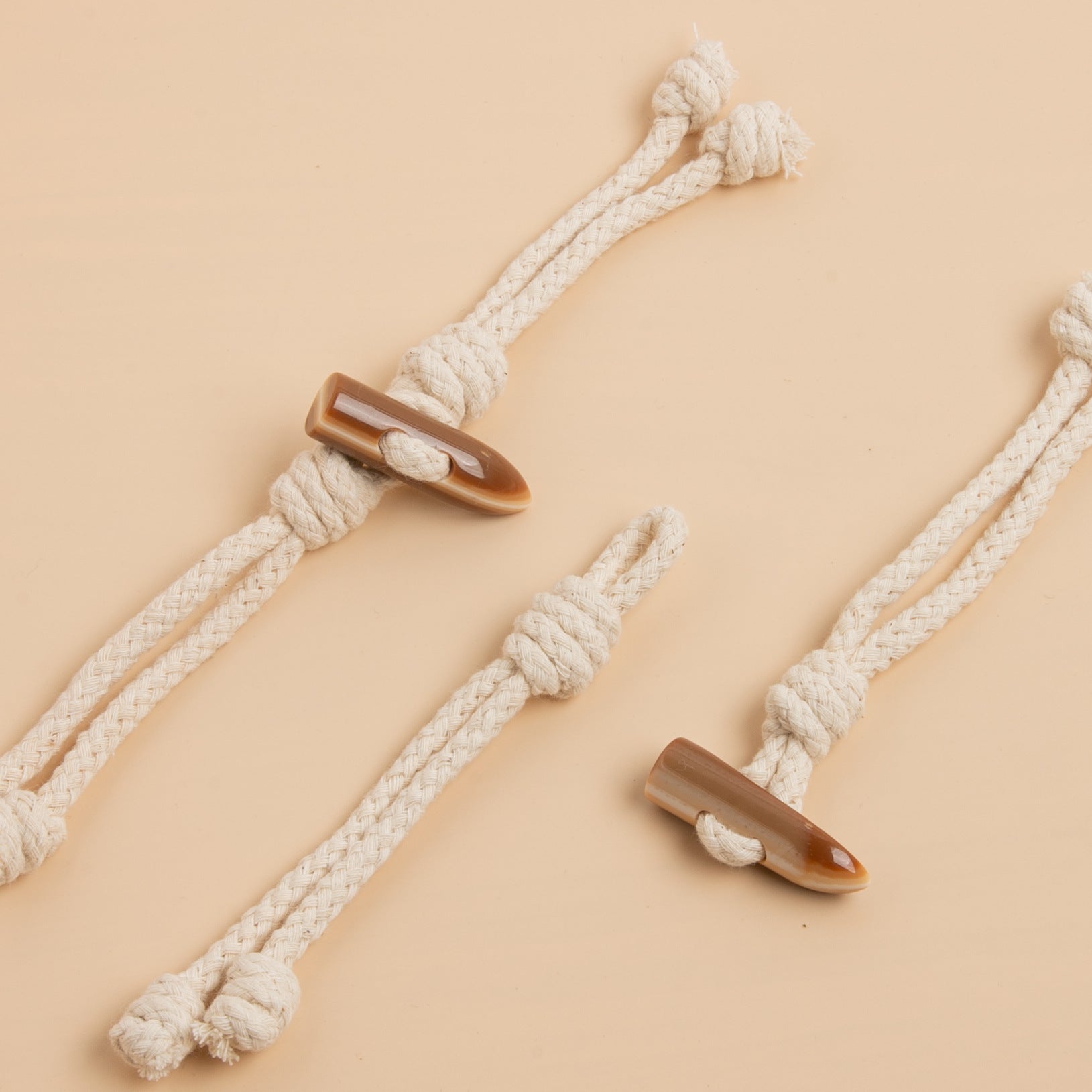 Beige rope tassel buckle set with resin horn-colored ends, details on knot and eyelets